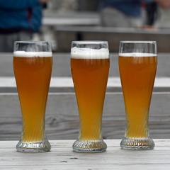 3 biergläser auf einem gartenlokaltisch