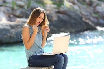 Excited woman finding online offer on the beach