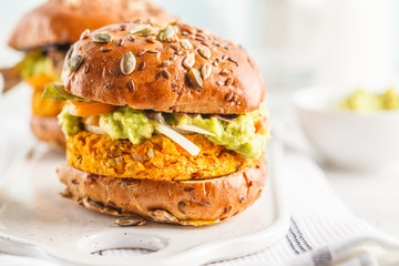 Vegan sweet potato (or pumpkin) burgers on white background. Vegetable burgers, avocado, vegetables and buns.