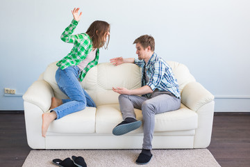 Bad relationship concept. Young couple sitting on couch at home having quarrel, offended wife and...