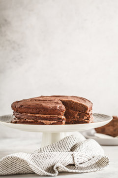 Vegan chocolate cake on a white dish for cake, copy space, light background.
