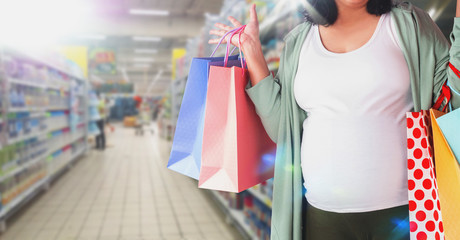 pregnant woman holding shoping bags in superstore
