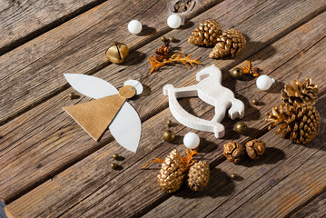 handmade paper angel and other Christmas ornaments on weathered old wooden table, with shades