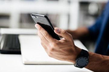 Man makes notes in a notebook on a table and keeps a phone in his hand