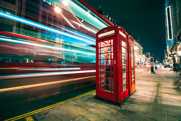 Light trails of a double decker bus next to the iconic telephone booth in London