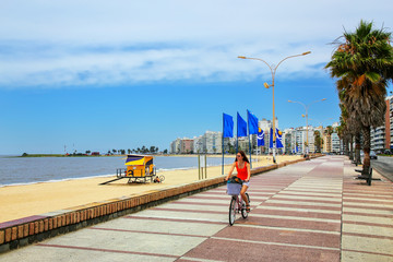 Woman biking on the boulevard along Pocitos beach in Montevideo,