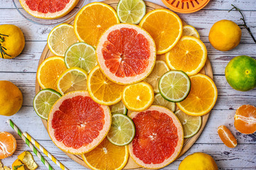 Mixed Fresh slices citrus fruit on a round wooden Board on a light background. Top view