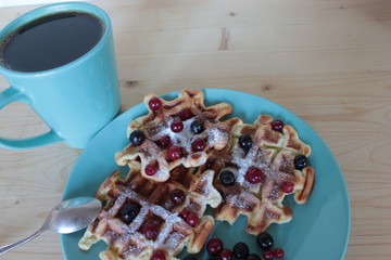 Cranberry waffles on a blue saucer and a cup of coffee.