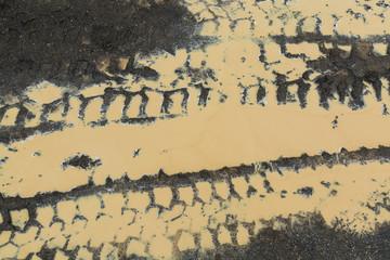 Traces of car tires on the puddle of mud