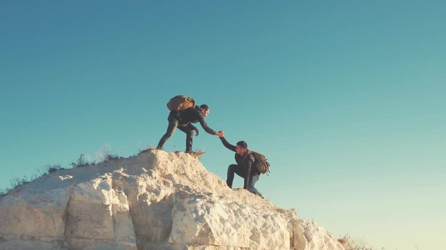 Climber helping teammate climb, the man with the backpack reached out a helping hand to his friend. Hiker helping friend while trekking on hill. Tourist man helps someone to climb the mountain.