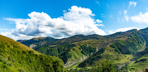 Fototapeta na wymiar Mountain hill path road panoramic landscape, clouds in the blue sky, summer sunny day