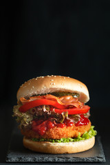 Burger on a stone stand on a black background.