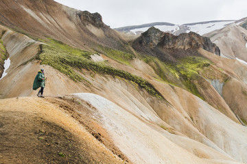 Fototapeta na wymiar Woman hiking in the colourful mountains of Landmannalaugar national park, Iceland