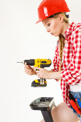 Woman using drill on ladder