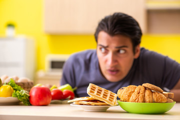 Man having hard choice between healthy and unhealthy food