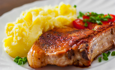 Grilled pork loin meat with mashed potatoes and salad in white plate