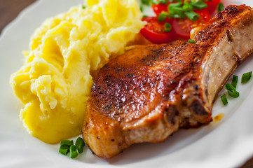 Grilled pork loin meat with mashed potatoes and salad in white plate