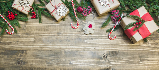 Christmas holiday banner - gifts, holly berries and decoration on wooden board. Holiday card. Top...
