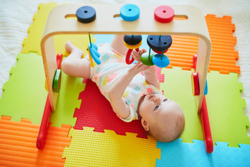 Smiling baby girl lying on play mat