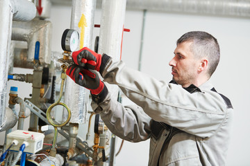heating engineer or plumber in boiler room installing or adjusting manometer