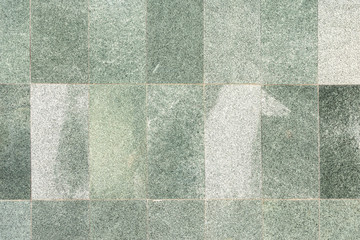 The wall is lined with green tiles, imitation marble. The texture of the stone panels.