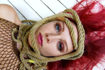 A red headed beauty lies down and seems to be in deep thought. She has an old rope  tied around her...