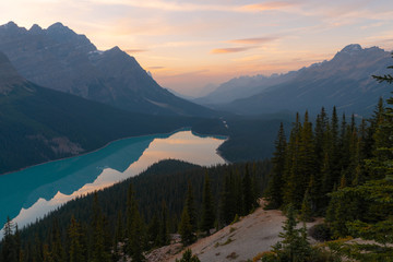 Obraz premium The orange glow of sunset over Peyto Lake in Banff National Park on a partly cloudy day