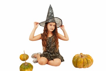 little girl with long hair in witch outfit on Halloween with pumpkins, emotionally expressions of...