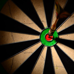 Dart arrow hitting in the target center of dartboard.