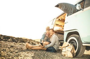 Hipster couple traveling together on oldtimer mini van transport - Travel lifestyle concept with...