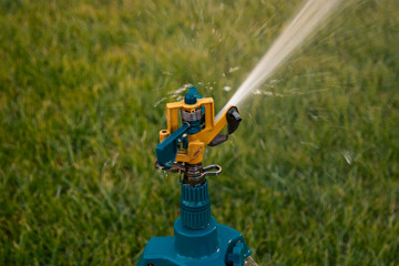 Head of tripod sprinkler watering grass