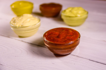 Different sauces in glass bowls on wooden table
