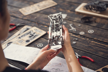 Careful concentrated lady sitting alone with the instructions and repairing the metal construction