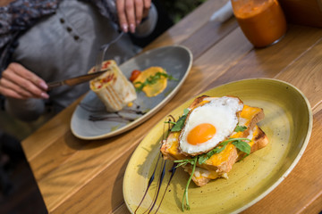 Closeup of egg breakfast sandwich with womens hands blurry in background