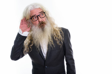 Studio shot of senior bearded businessman thinking while listeni