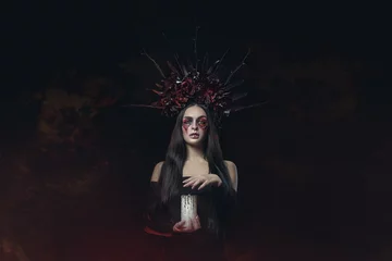 Selbstklebende Fototapeten Schreckliches Halloween-Vampir-Frauenporträt. Schönheit Vampir Hexe Dame mit Blut am Mund posiert im tiefen Wald. Mode-Kunst-Design. hält eine Kerze in den Händen und liest Flüche © oes