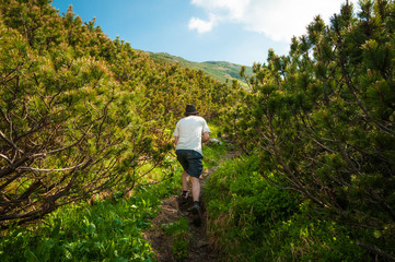 Obraz premium Man with white t-shirt and hat walking in the mountains