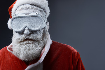 Close up portrait of bearded old man in Santa costume covered with snow. Copy space on right side