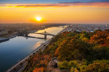 Budapest, Hungary - Panoramic skyline view of Budapest with beautiful autumn foliage, Liberty Bridge (Szabadsag Hid) and lookout on Gellert Hill and colourful sky at sunrise