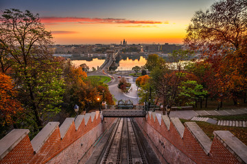Budapest, Hungary - Autumn in Budapest. The Castle Hill Funicular (Budavári Siklo) with the Szechenyi Chain Bridge and St. Stephen's Basilica at sunrise with autumn foliage