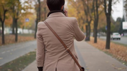 young woman pulls phone out of her bag to answer call