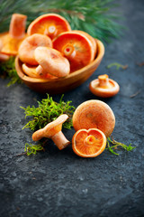 Obraz na płótnie Canvas Raw wild Saffron milk cap mushrooms on dark old rustic background. Lactarius deliciosus. Rovellons, Niscalos. Organic fresh mushrooms closeup on a table