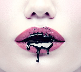 Halloween-feestmake-up, gotische stijl. Zwarte verf druipt van de lippen van een mooi modelmeisje. Schoonheid vrouw gezicht close-up