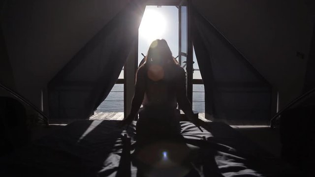 A young girl woke up early in the morning in bed with a view of the sea and a terrace