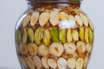 Rotating jar with nuts in honey. Close-up side view.