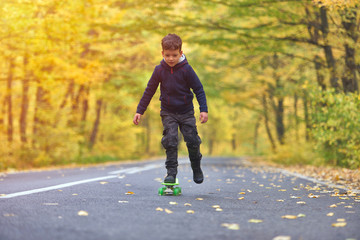 Fototapeta premium Kid skateboarder doing skateboard tricks in autumn environment