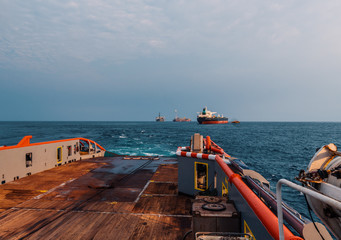 Anchor-handling Tug Supply AHTS vessel during dynamic positioning DP operations near FPSO tanker....