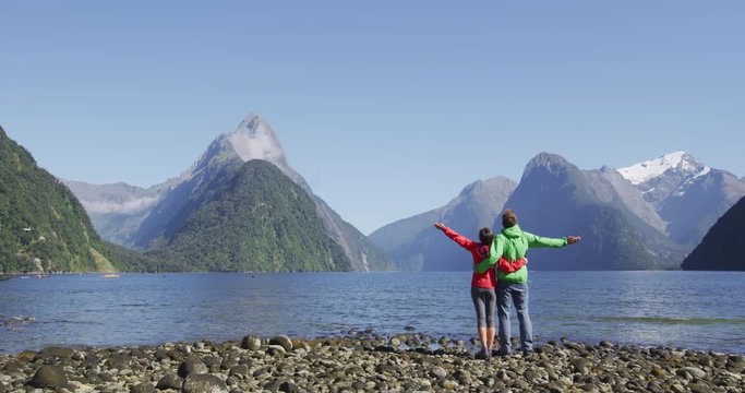 Travel in nature - happy free tourists with wanderlust enjoying Milford Sound hiking in New Zealand enjoying iconic view of Mitre Peak, Fjord and famous tourist destination in Fiordland National Park,