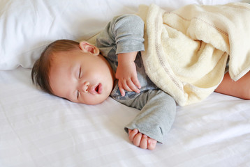 Newborn baby boy sleeping on bed with the blanket.