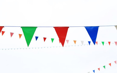 Colorful triangular Flags Hanging in the white sky outdoor.